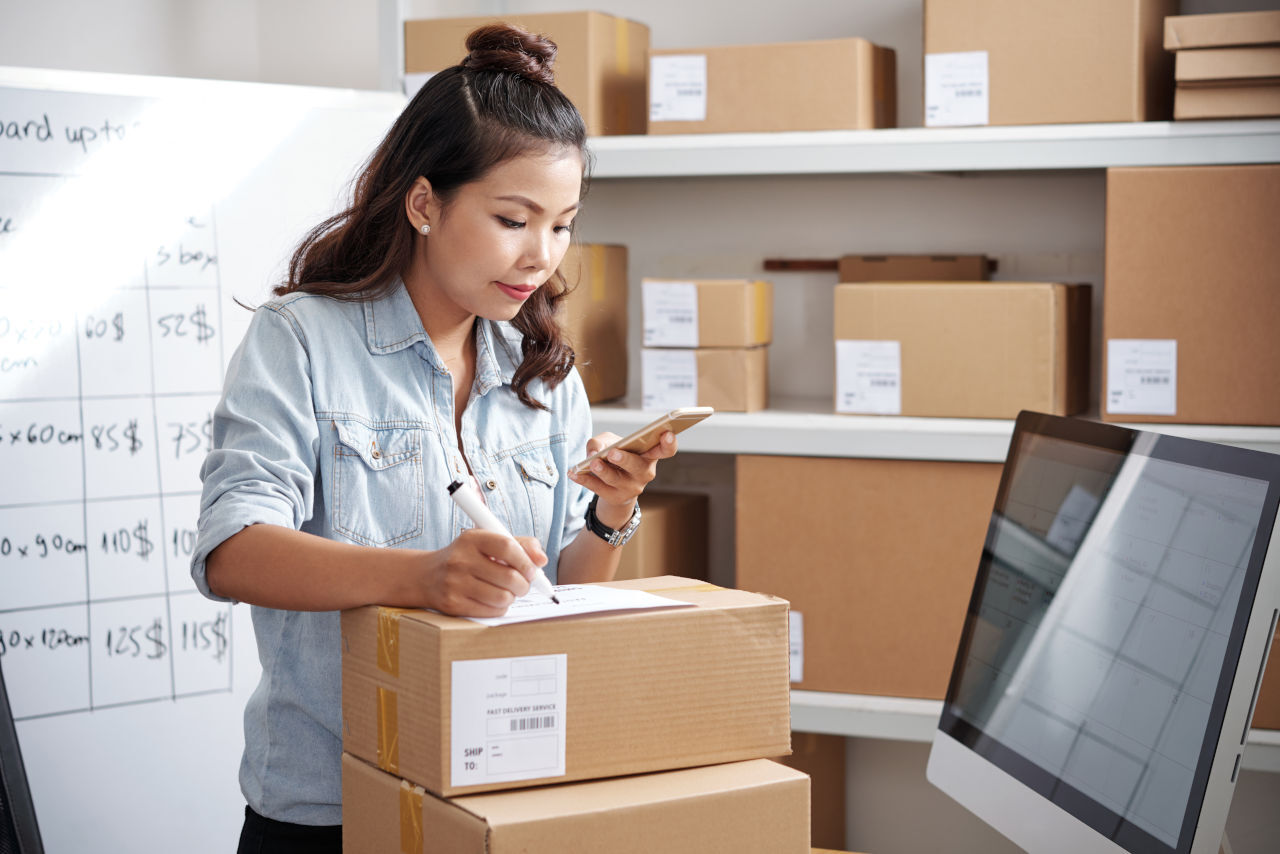 Woman working in an ecommerce inventory, preparing a package to be sent to a customer.