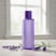 Cosmetic product mockup showing a translucent purple bottle placed on a light table.
