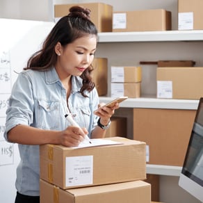 Woman working in an ecommerce inventory, preparing a package to be sent to a customer.